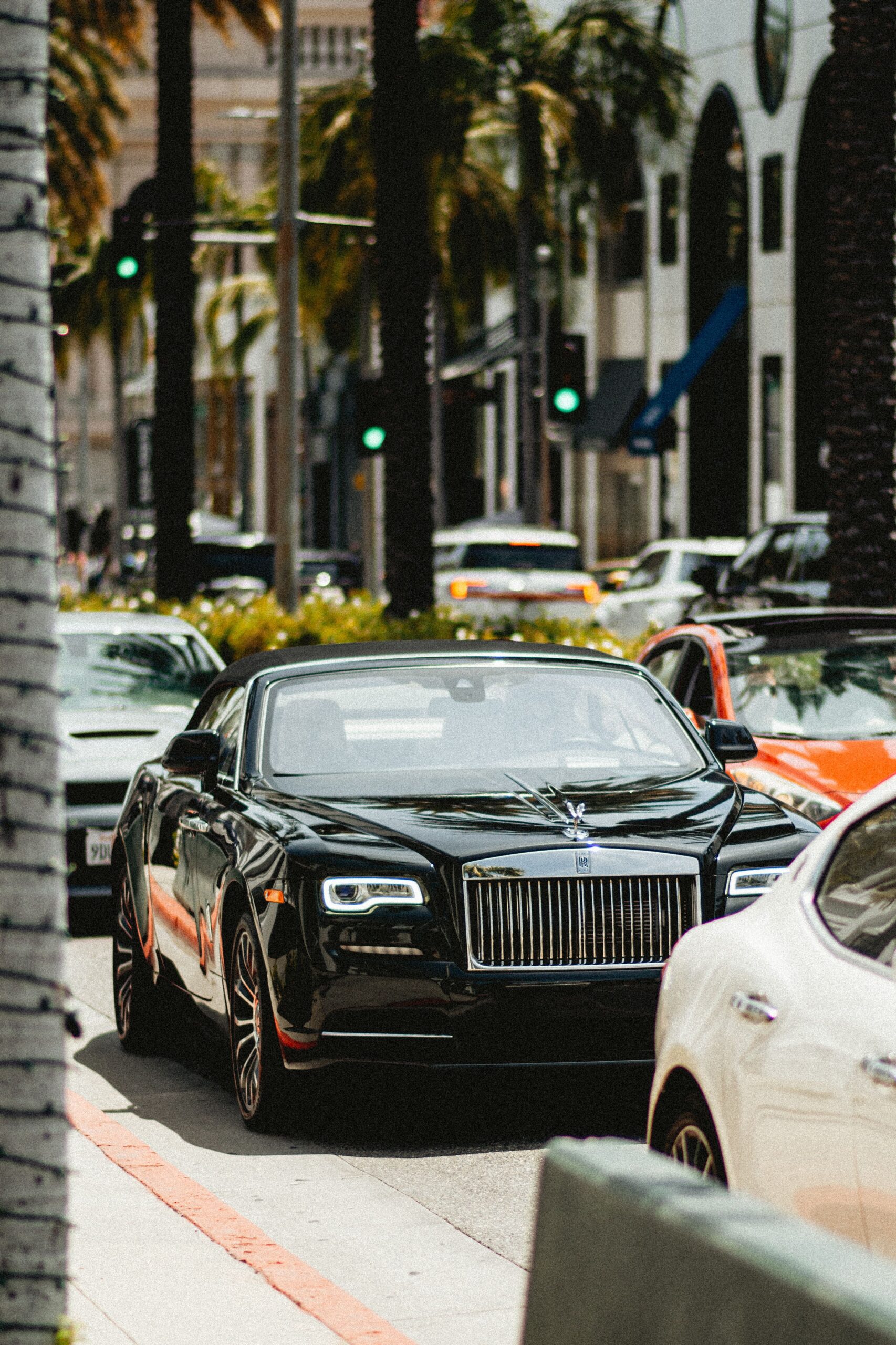 A black luxury convertible car navigating through traffic in Beverly Hills, California.